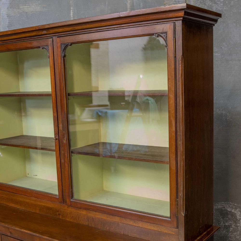 An Edwardian mahogany shop fitting bookcase featuring a three-door glazed upper section with a pale painted interior above a four-door panelled cupboard base. View XIV