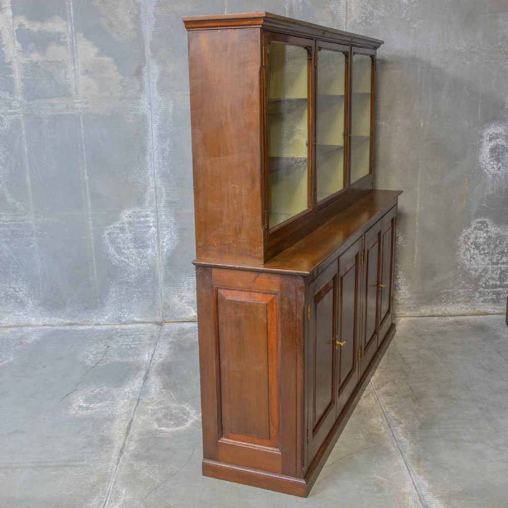 An Edwardian mahogany shop fitting bookcase featuring a three-door glazed upper section with a pale painted interior above a four-door panelled cupboard base. View XVI
