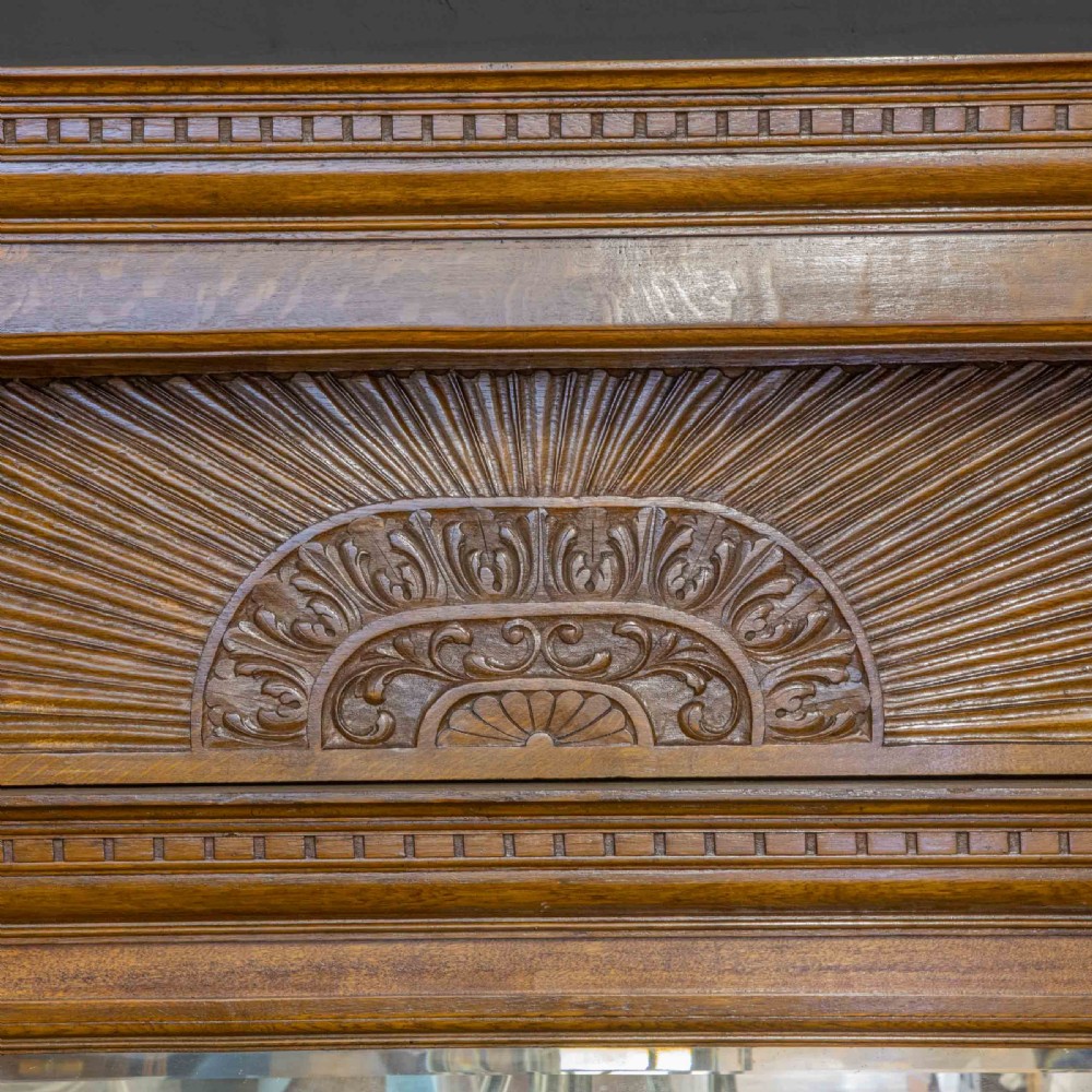 A late Victorian carved oak sideboard with a mirrored backboard superstructure, detailed relief carvings, turned pillars, and claw feet. View III