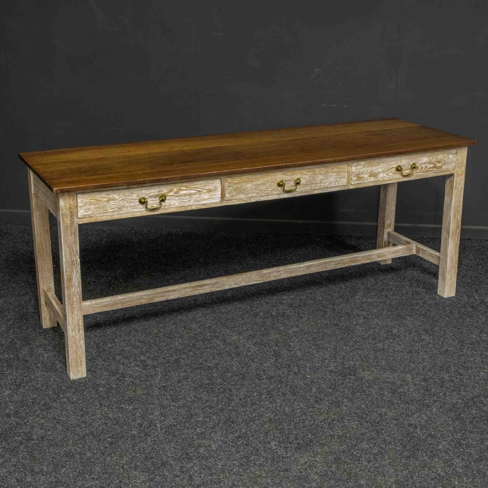 A long early 20th-century wooden console table featuring a polished brown top, whitewashed three-drawer apron, brass drop handles, and straight legs with an H-stretcher.