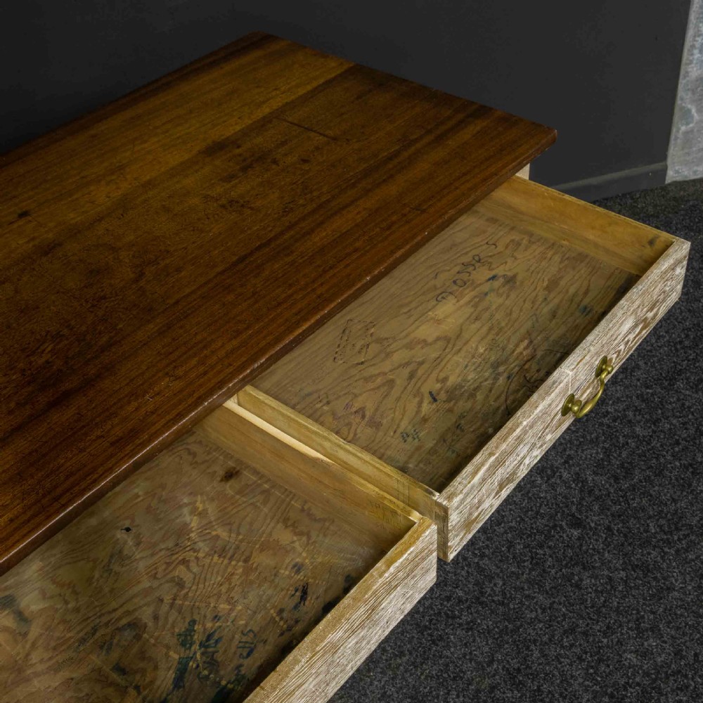 A long early 20th-century wooden console table featuring a polished brown top, whitewashed three-drawer apron, brass drop handles, and straight legs with an H-stretcher. View II
