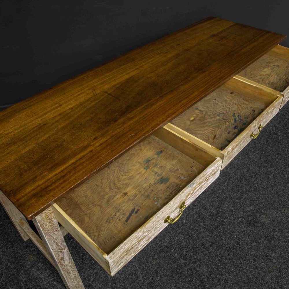 A long early 20th-century wooden console table featuring a polished brown top, whitewashed three-drawer apron, brass drop handles, and straight legs with an H-stretcher. View III