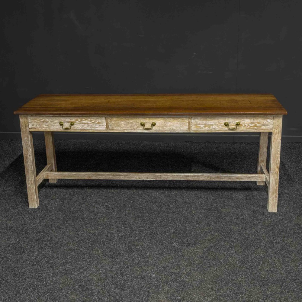 A long early 20th-century wooden console table featuring a polished brown top, whitewashed three-drawer apron, brass drop handles, and straight legs with an H-stretcher. View IV