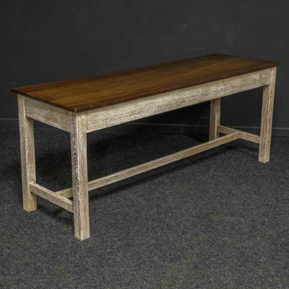A long early 20th-century wooden console table featuring a polished brown top, whitewashed three-drawer apron, brass drop handles, and straight legs with an H-stretcher. View VI
