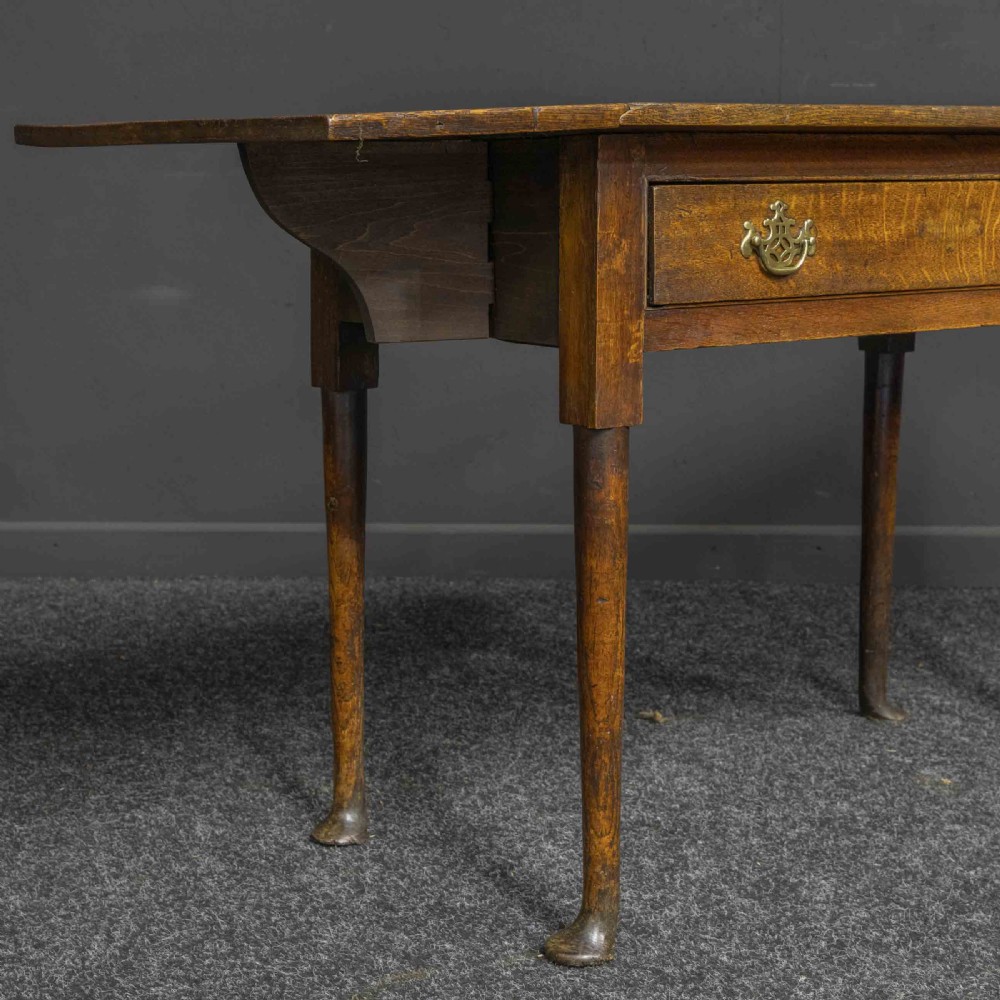 A seventeenth-century warm brown oak sofa table featuring side drop-leaf extensions, a single drawer with brass handles, and tapered legs ending in pad feet. View II