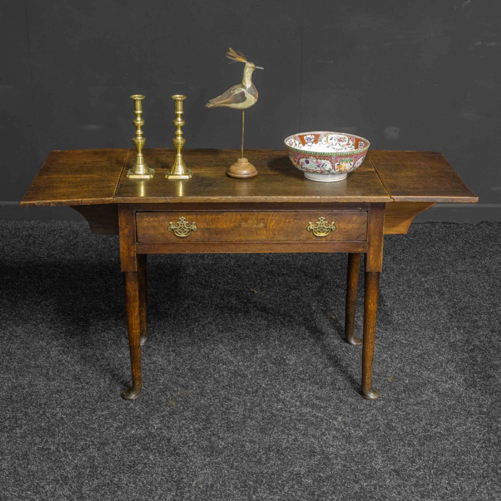 A seventeenth-century warm brown oak sofa table featuring side drop-leaf extensions, a single drawer with brass handles, and tapered legs ending in pad feet. View IV