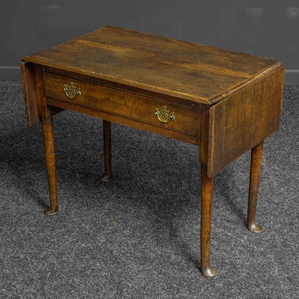A seventeenth-century warm brown oak sofa table featuring side drop-leaf extensions, a single drawer with brass handles, and tapered legs ending in pad feet. View VII