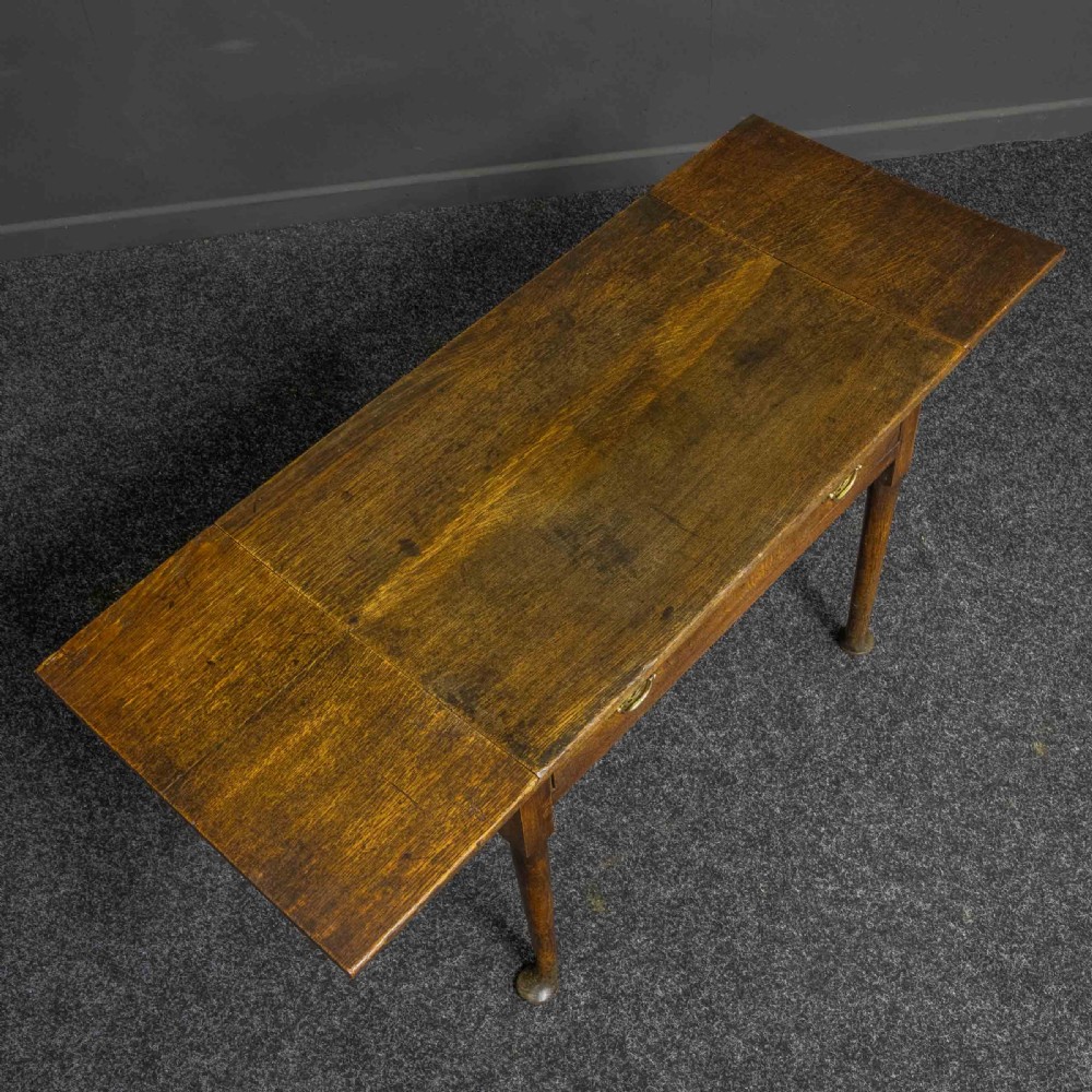 A seventeenth-century warm brown oak sofa table featuring side drop-leaf extensions, a single drawer with brass handles, and tapered legs ending in pad feet. View VIII