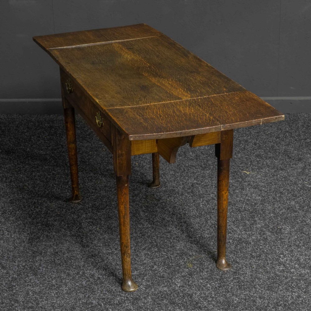 A seventeenth-century warm brown oak sofa table featuring side drop-leaf extensions, a single drawer with brass handles, and tapered legs ending in pad feet. View XI