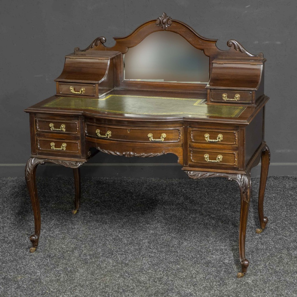 A late Victorian dark mahogany ladies writing desk featuring a green leather inset top, raised mirror superstructure, small side drawers, carved cabriole legs, and brass handles. View II