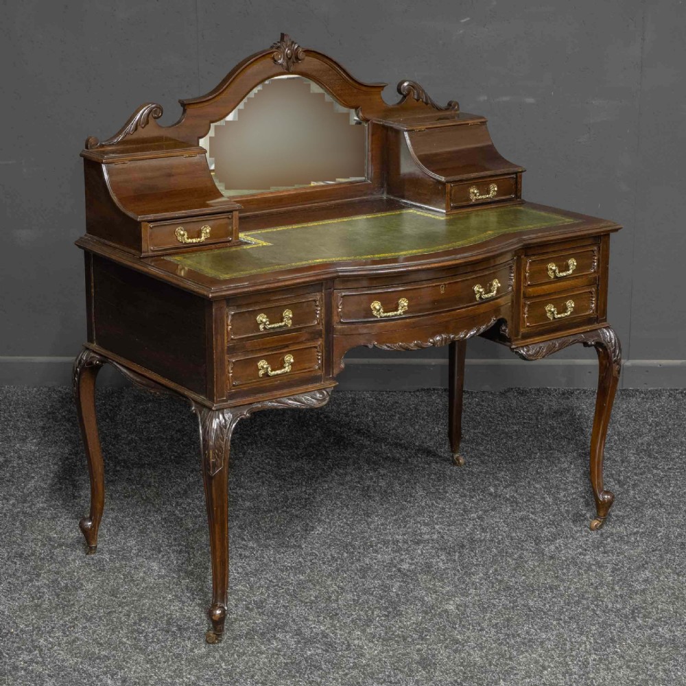 A late Victorian dark mahogany ladies writing desk featuring a green leather inset top, raised mirror superstructure, small side drawers, carved cabriole legs, and brass handles. View III