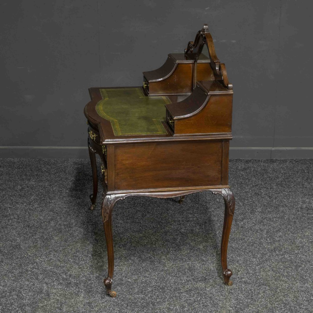 A late Victorian dark mahogany ladies writing desk featuring a green leather inset top, raised mirror superstructure, small side drawers, carved cabriole legs, and brass handles. View IV