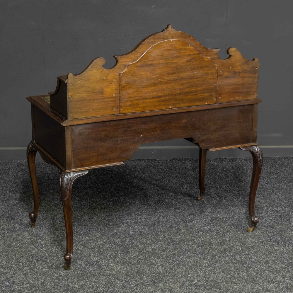 A late Victorian dark mahogany ladies writing desk featuring a green leather inset top, raised mirror superstructure, small side drawers, carved cabriole legs, and brass handles. View V