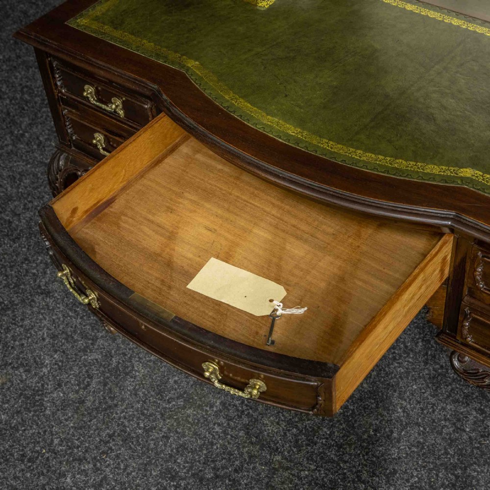 A late Victorian dark mahogany ladies writing desk featuring a green leather inset top, raised mirror superstructure, small side drawers, carved cabriole legs, and brass handles. View VI