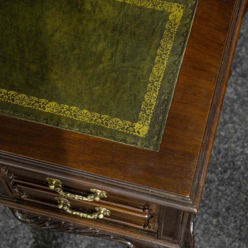 A late Victorian dark mahogany ladies writing desk featuring a green leather inset top, raised mirror superstructure, small side drawers, carved cabriole legs, and brass handles. View X