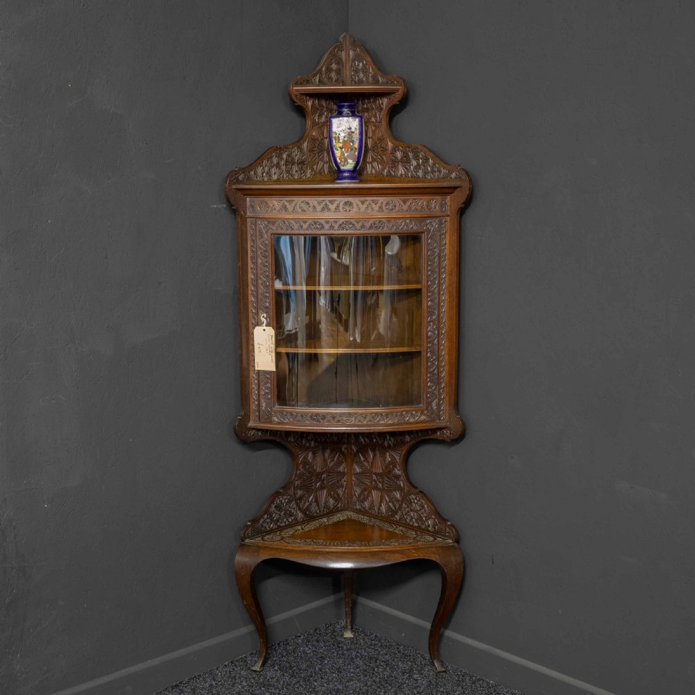 Carved dark walnut corner display cabinet featuring a single glazed door, decorative carved panels, upper and lower shelves, and cabriole legs. View III