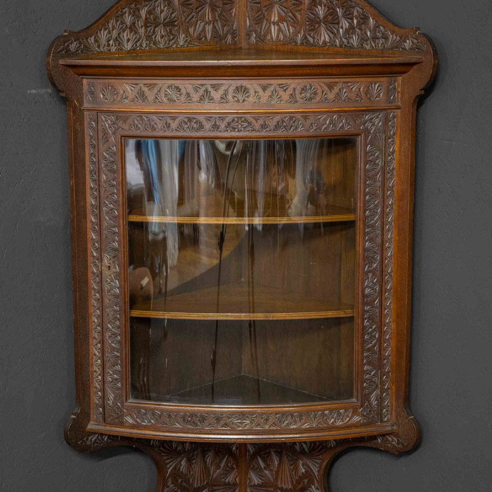 Carved dark walnut corner display cabinet featuring a single glazed door, decorative carved panels, upper and lower shelves, and cabriole legs. View IV