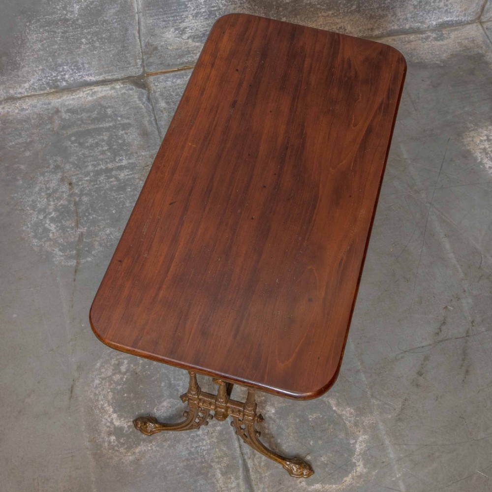A rectangular dark wood tabletop mounted on a gold-painted cast iron base with stretchers and ornamental feet. View VI