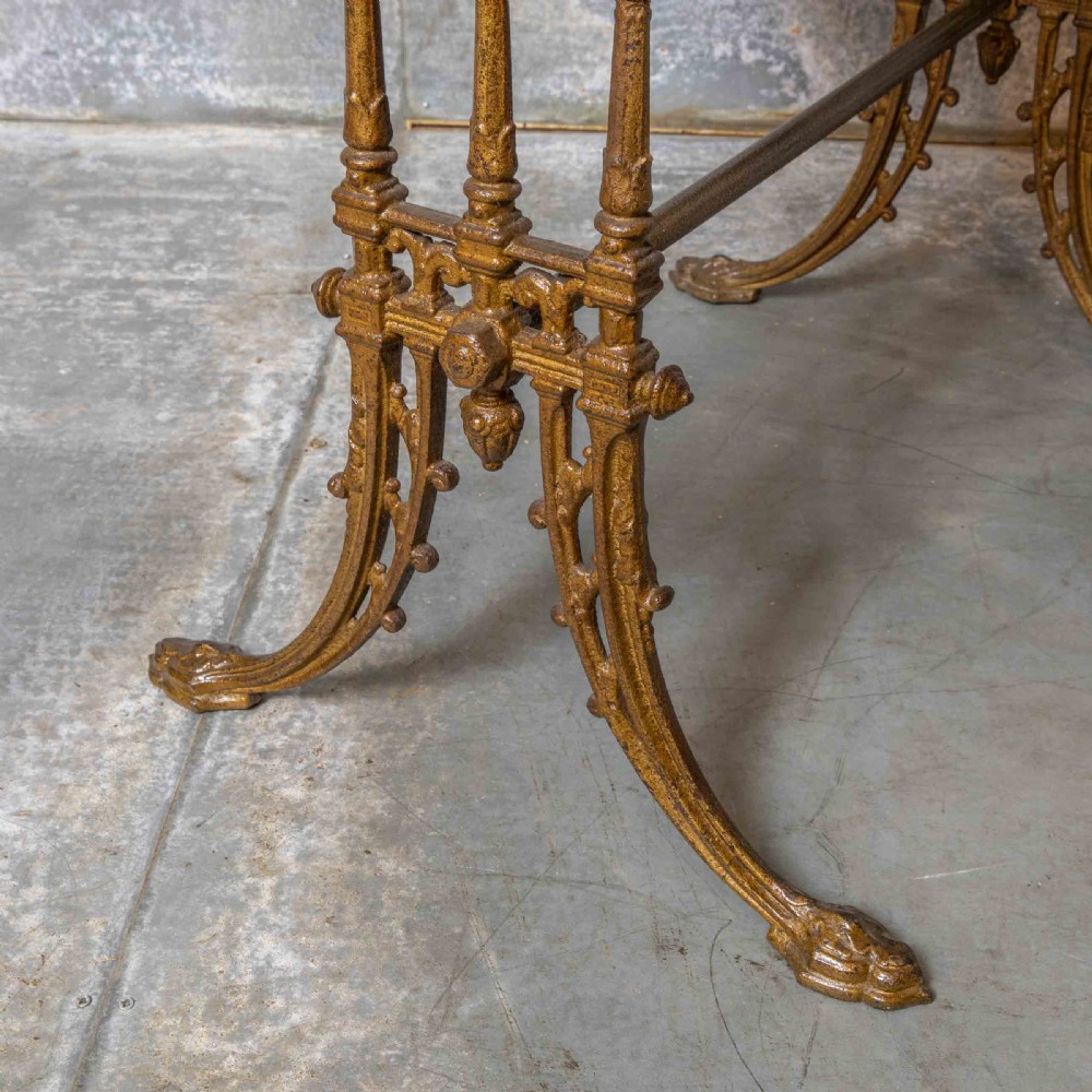 A rectangular dark wood tabletop mounted on a gold-painted cast iron base with stretchers and ornamental feet. View VIII
