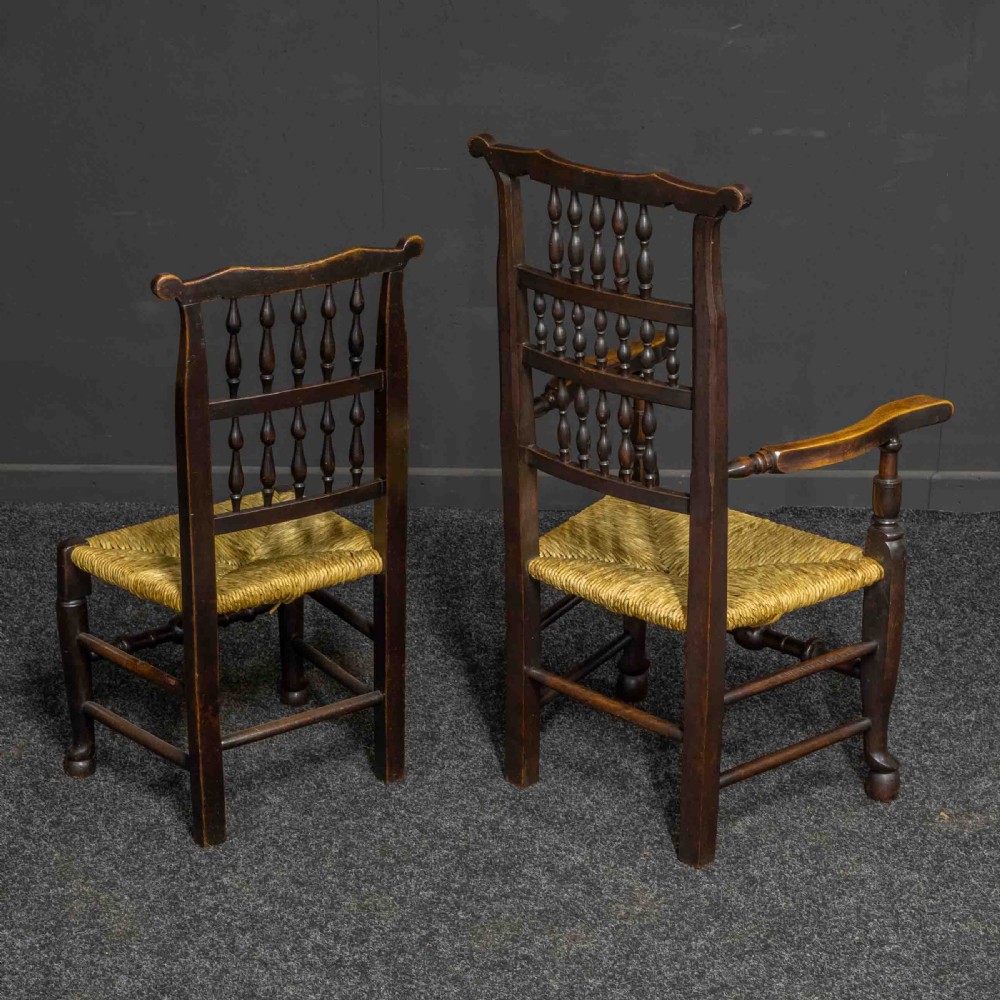 A set of eight Georgian dark oak spindleback dining chairs featuring two carver armchairs and six single side chairs with woven rush seats. View V