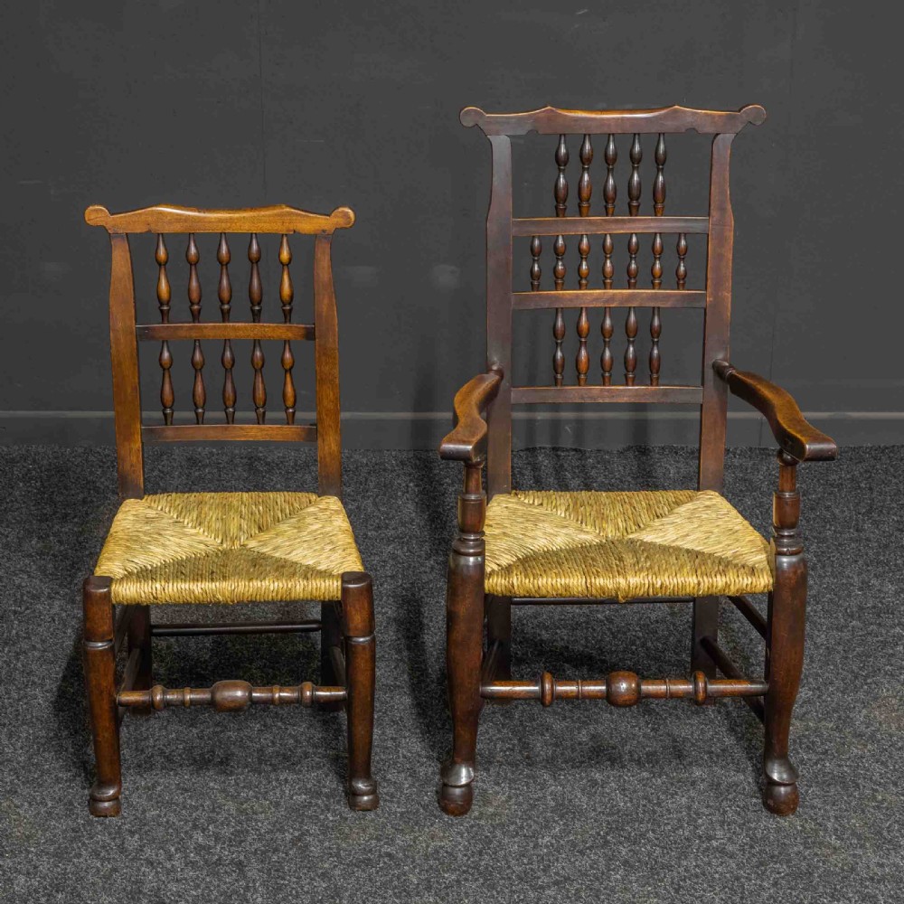 A set of eight Georgian dark oak spindleback dining chairs featuring two carver armchairs and six single side chairs with woven rush seats. View VI