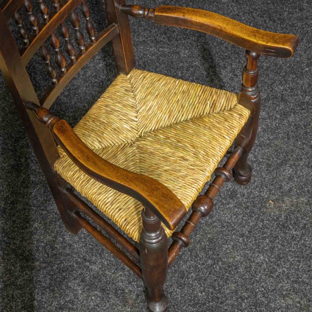 A set of eight Georgian dark oak spindleback dining chairs featuring two carver armchairs and six single side chairs with woven rush seats. View VII