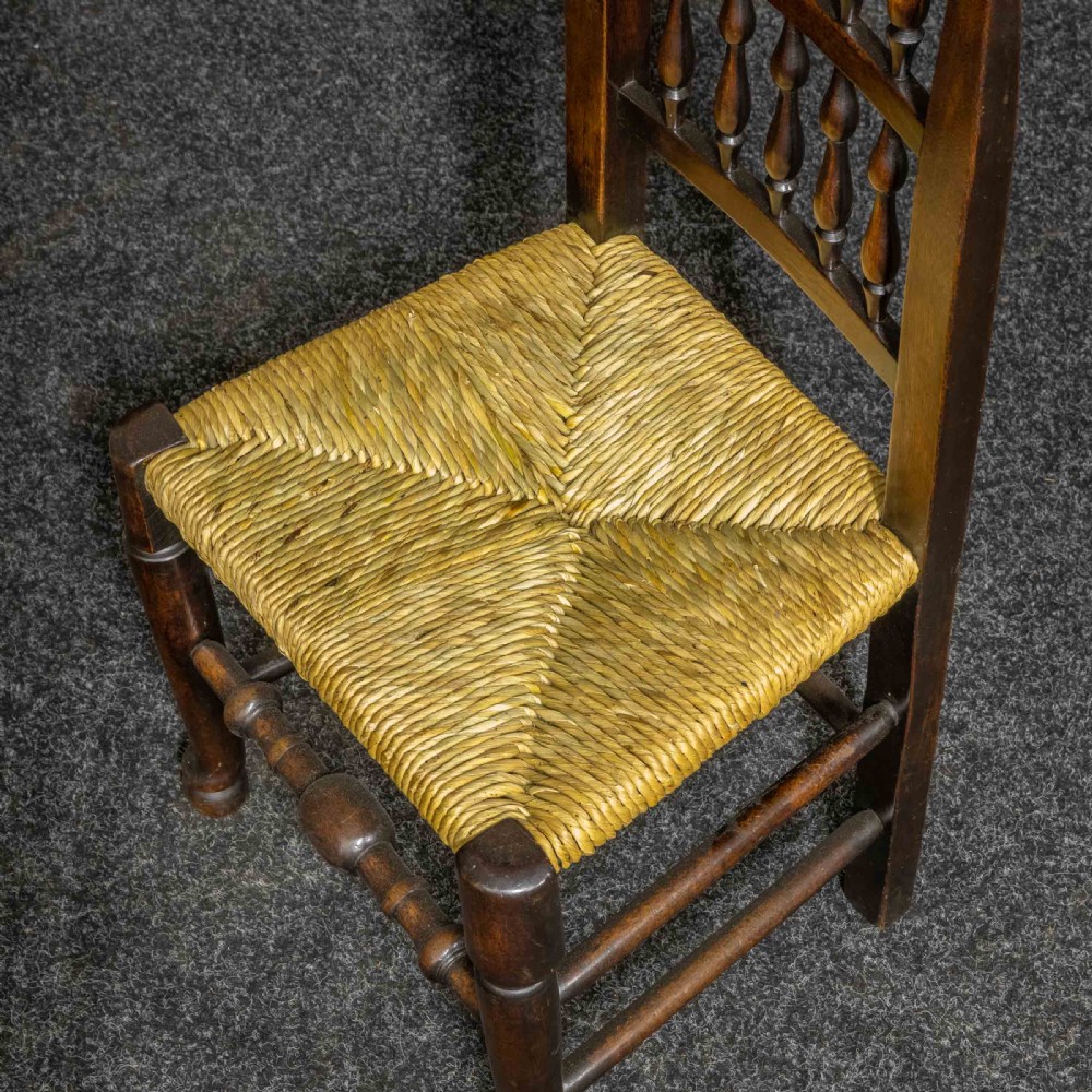 A set of eight Georgian dark oak spindleback dining chairs featuring two carver armchairs and six single side chairs with woven rush seats. View VIII