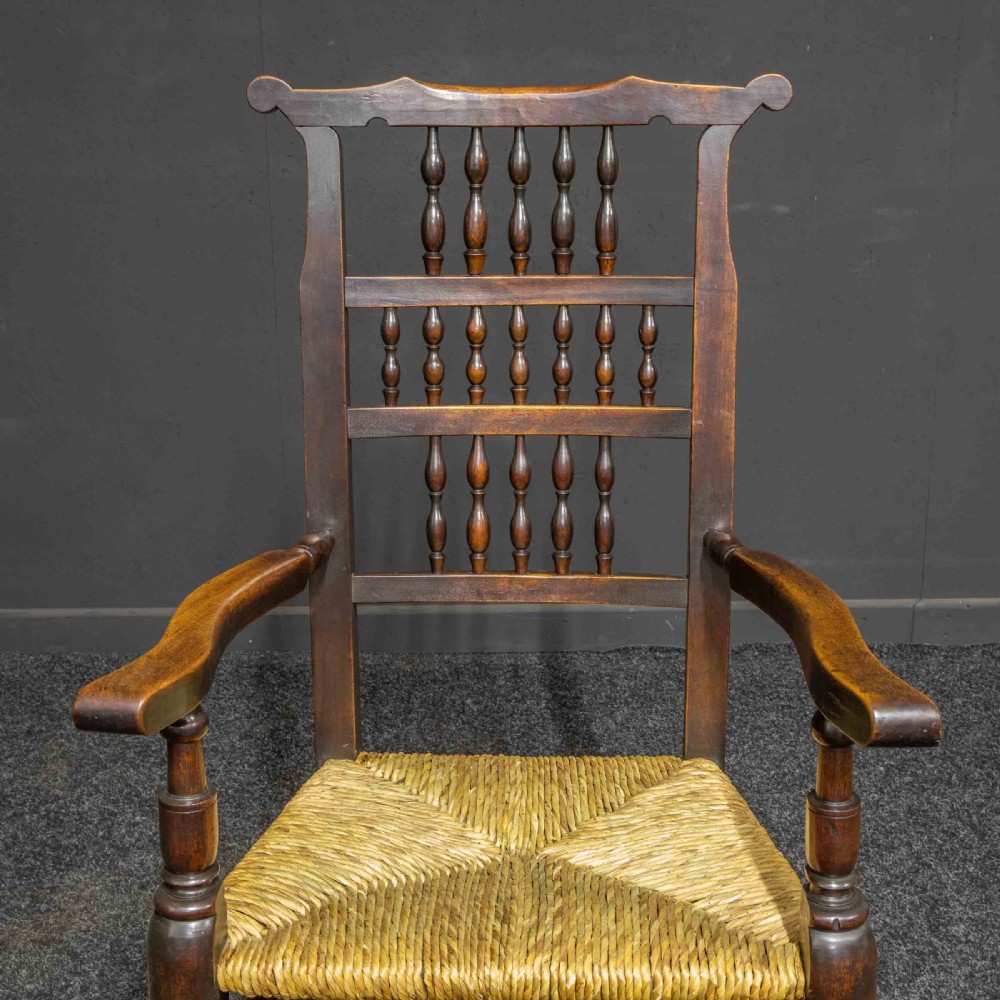 A set of eight Georgian dark oak spindleback dining chairs featuring two carver armchairs and six single side chairs with woven rush seats. View IX