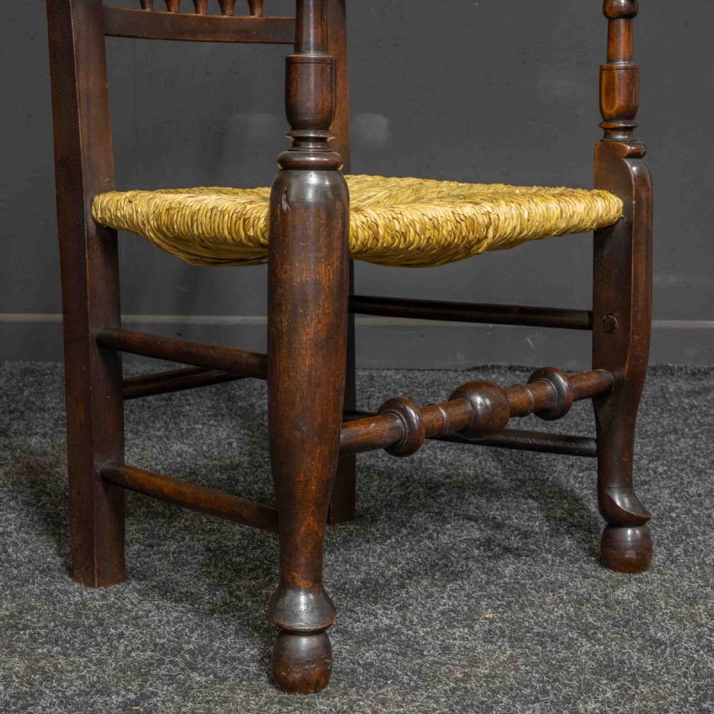 A set of eight Georgian dark oak spindleback dining chairs featuring two carver armchairs and six single side chairs with woven rush seats. View X