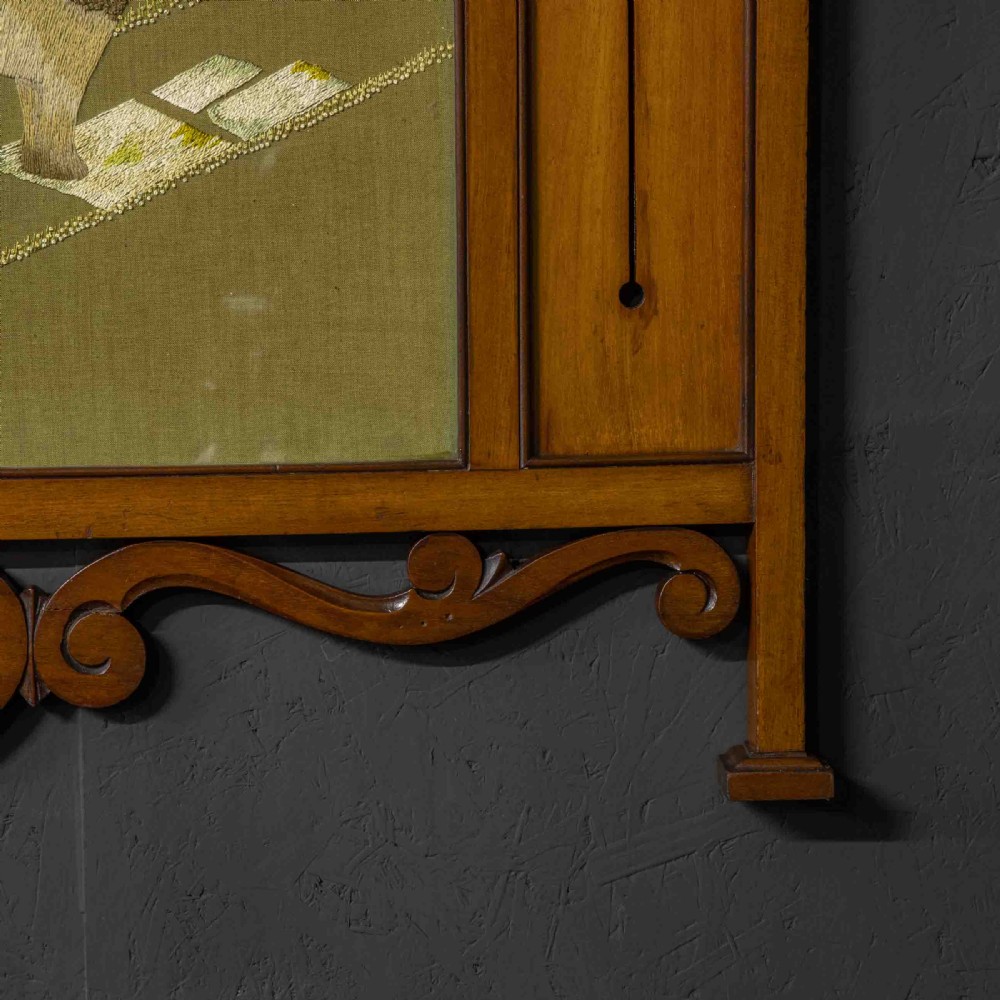 An Edwardian carved mahogany overmantel frame featuring a central embroidered panel depicting a figure with a lion, topped with scrollwork and an inverted heart cutout at the base. View VIII