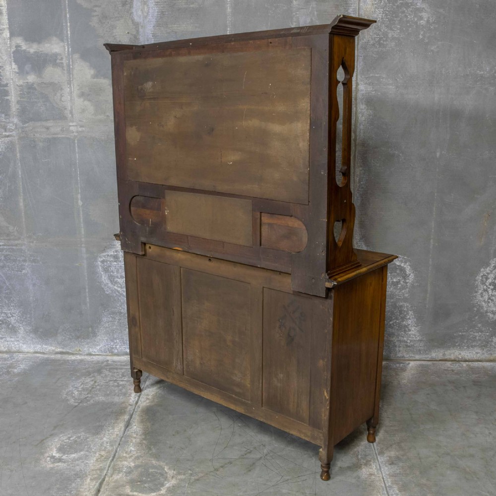 A Victorian walnut sideboard featuring carved panelled cupboard doors, drawers with brass handles, and a mirrored upper shelf structure. View V