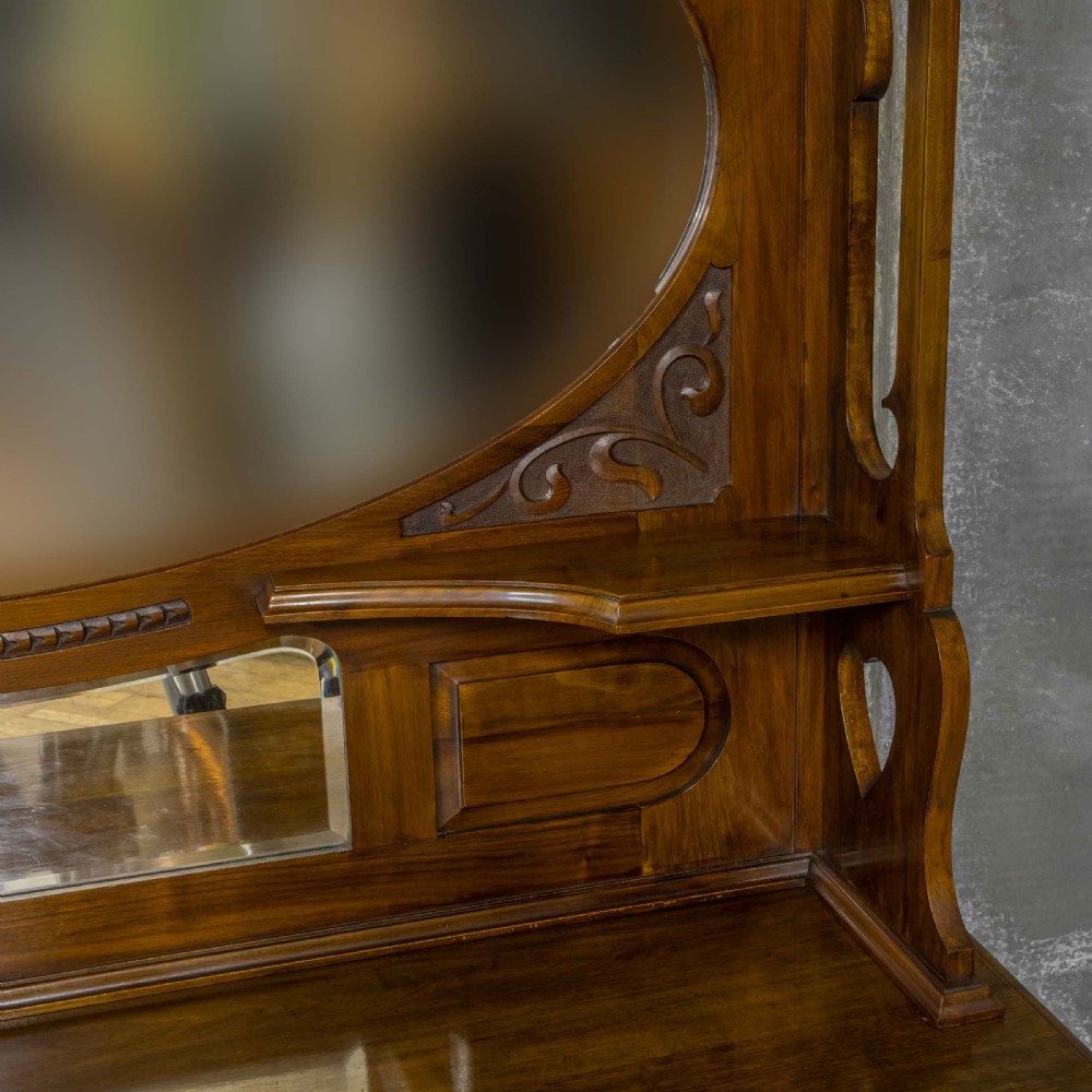 A Victorian walnut sideboard featuring carved panelled cupboard doors, drawers with brass handles, and a mirrored upper shelf structure. View VIII