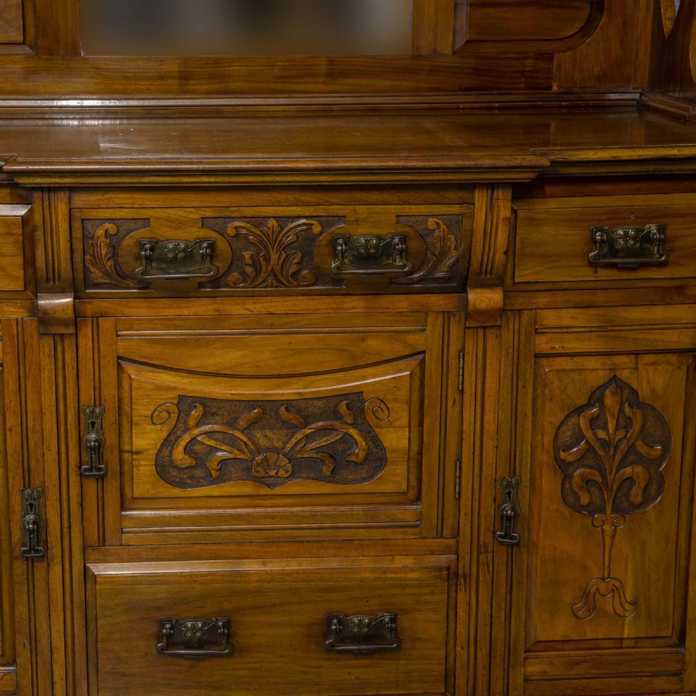 A Victorian walnut sideboard featuring carved panelled cupboard doors, drawers with brass handles, and a mirrored upper shelf structure. View XII