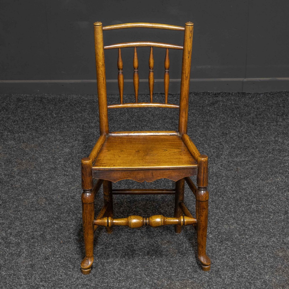 A set of sixteen 18th-century country oak dining chairs featuring spindle backrests, wooden panel seats, turned legs, and stretchers. View II