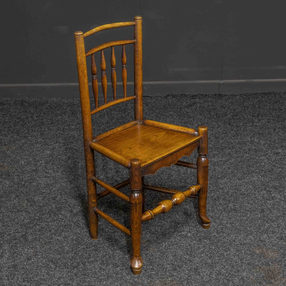 A set of sixteen 18th-century country oak dining chairs featuring spindle backrests, wooden panel seats, turned legs, and stretchers. View III