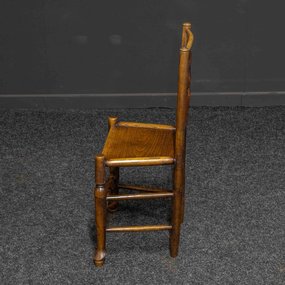 A set of sixteen 18th-century country oak dining chairs featuring spindle backrests, wooden panel seats, turned legs, and stretchers. View V