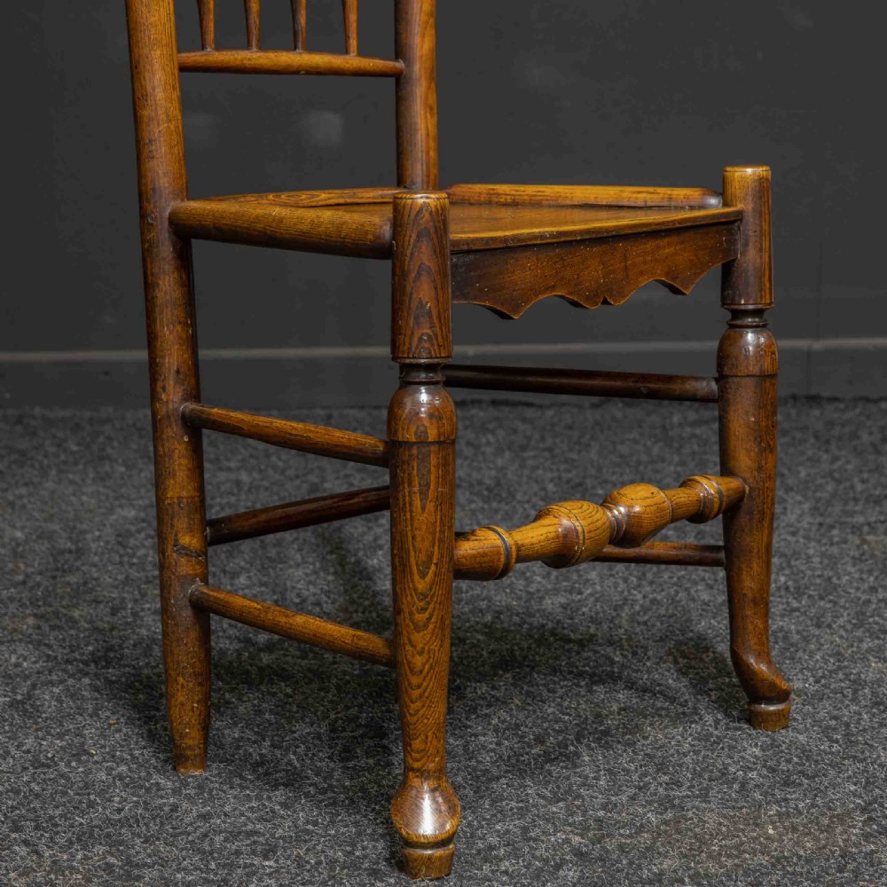 A set of sixteen 18th-century country oak dining chairs featuring spindle backrests, wooden panel seats, turned legs, and stretchers. View X