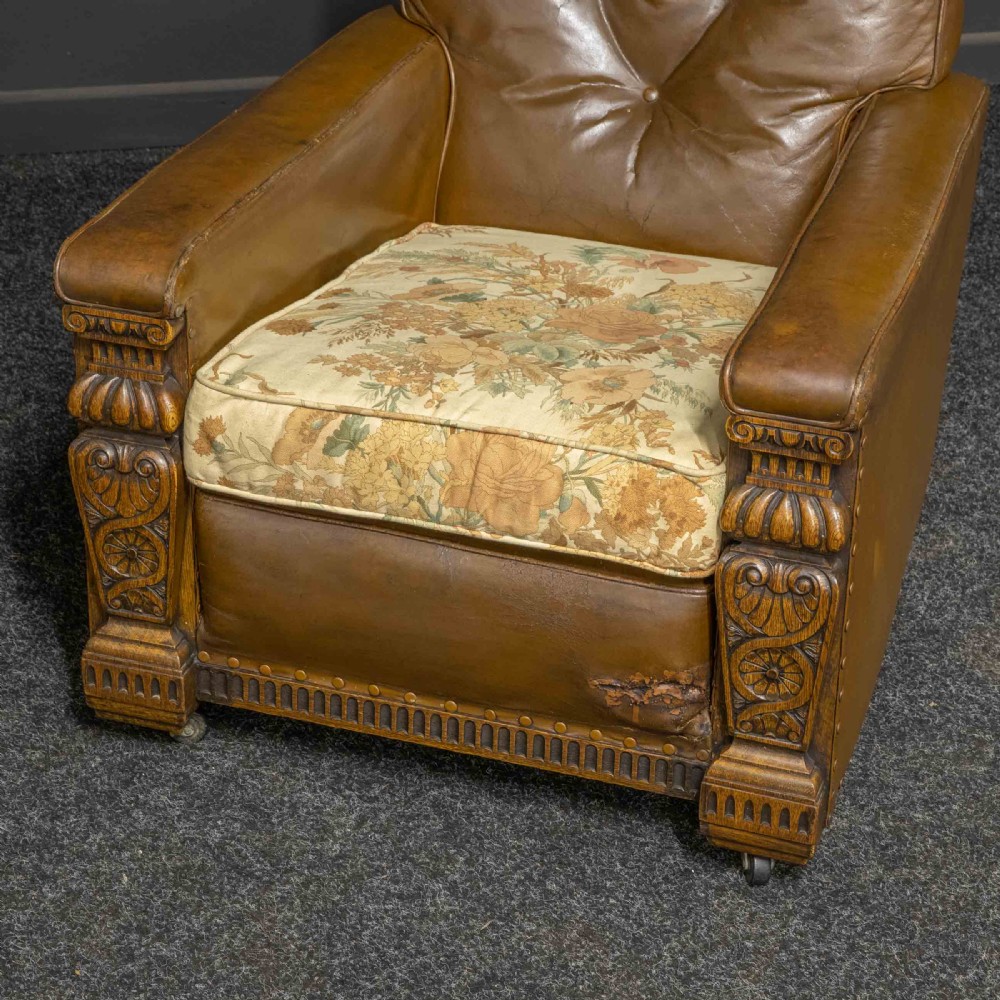 A pair of early 20th-century tan leather armchairs featuring buttoned backs, carved timber front pilasters, and floral patterned fabric seat cushions. View VIII