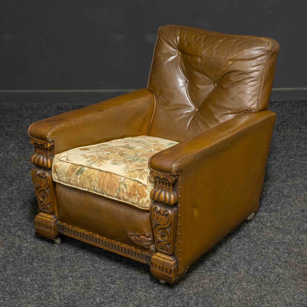 A pair of early 20th-century tan leather armchairs featuring buttoned backs, carved timber front pilasters, and floral patterned fabric seat cushions. View XIII