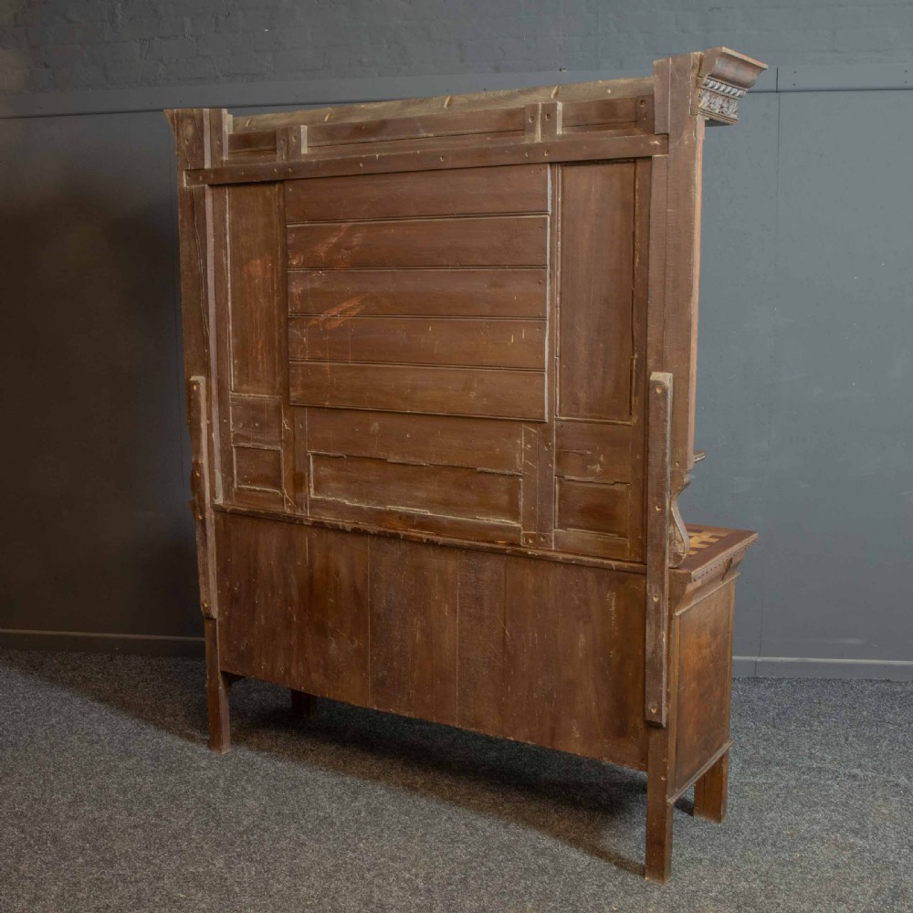 A carved oak Arts and Crafts dresser featuring a mirror back upper section, carved leaf panels, checkerboard inlay counter, and lower cupboards. View XVIII
