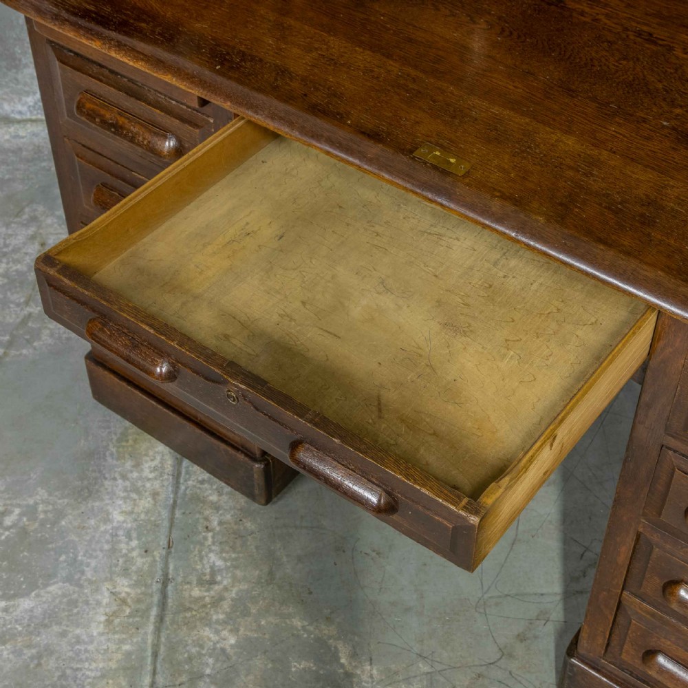 An Edwardian dark oak roll top desk featuring an open slatted tambour hood, fitted interior pigeonhole compartments, and twin pedestals with carved wooden drawer handles. View V