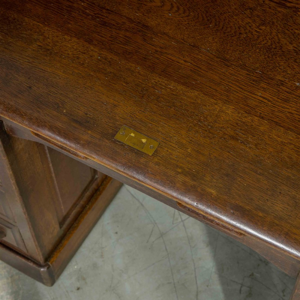 An Edwardian dark oak roll top desk featuring an open slatted tambour hood, fitted interior pigeonhole compartments, and twin pedestals with carved wooden drawer handles. View IX
