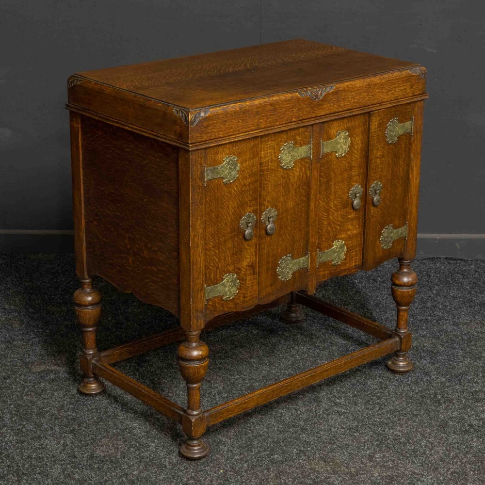An early 20th-century medium oak wind-up cabinet gramophone with brass strap hinges, drop handles, turned legs, and an open top lid showing the turntable mechanism. View XIII
