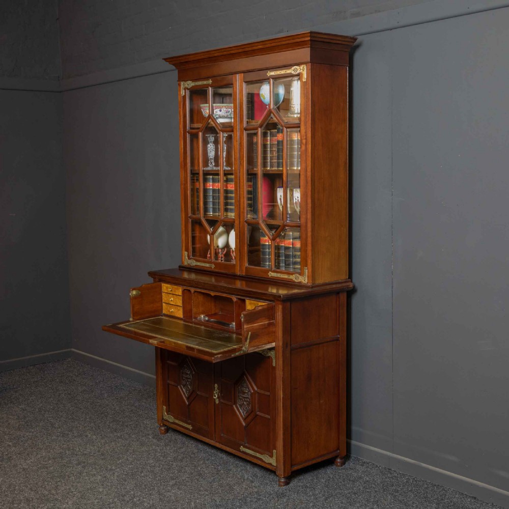 A tall Victorian walnut secretaire bookcase featuring a glazed upper display section, a drop-down desk compartment, and carved double doors at the base with decorative brass mounts. View III