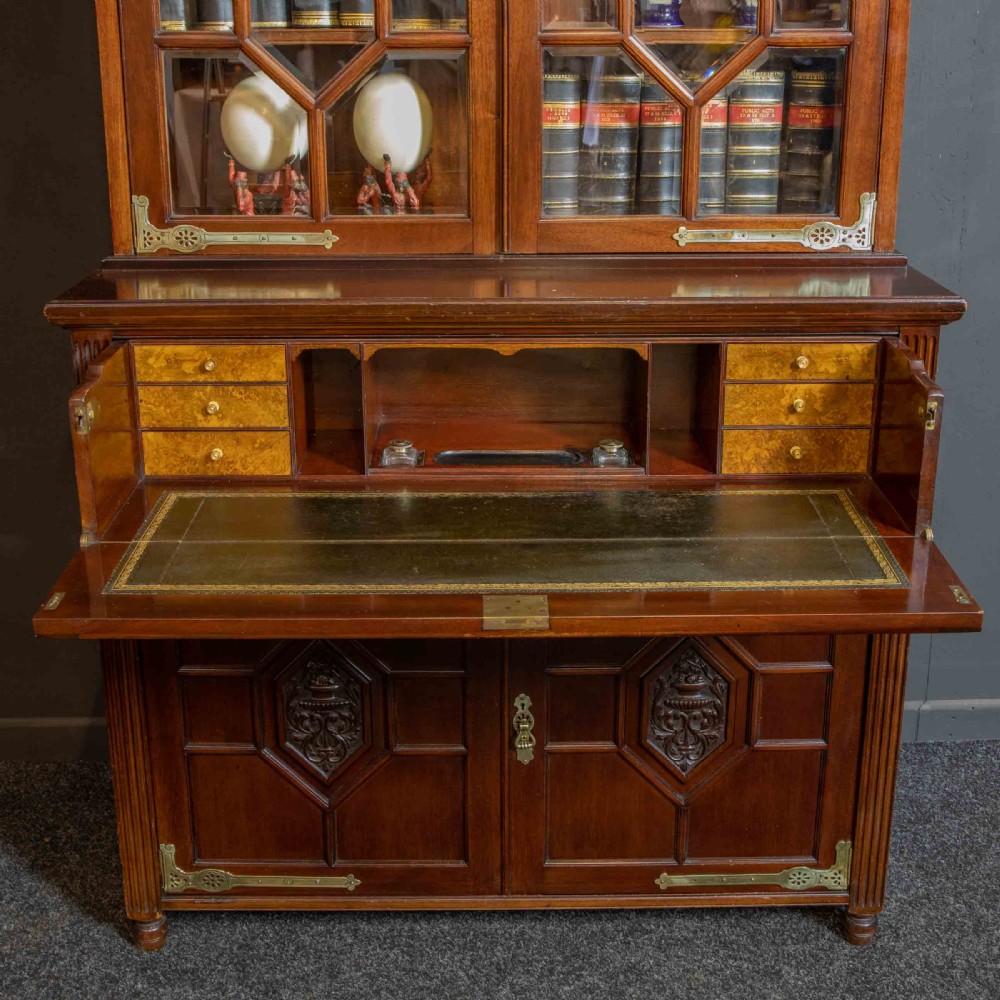 A tall Victorian walnut secretaire bookcase featuring a glazed upper display section, a drop-down desk compartment, and carved double doors at the base with decorative brass mounts. View IX