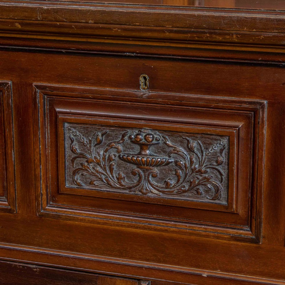 A tall Victorian walnut secretaire bookcase featuring a glazed upper display section, a drop-down desk compartment, and carved double doors at the base with decorative brass mounts. View X