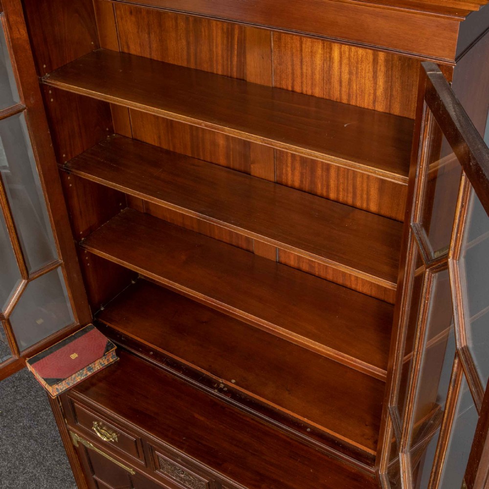 A tall Victorian walnut secretaire bookcase featuring a glazed upper display section, a drop-down desk compartment, and carved double doors at the base with decorative brass mounts. View XV