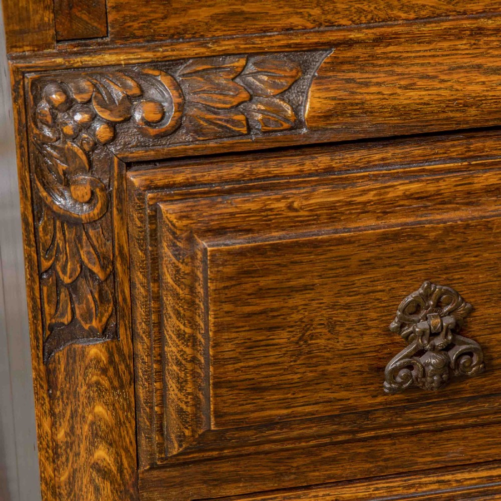 An early 20th-century dark oak writing bureau with a carved oval floral motif on the sloped flap above two drawers. View III