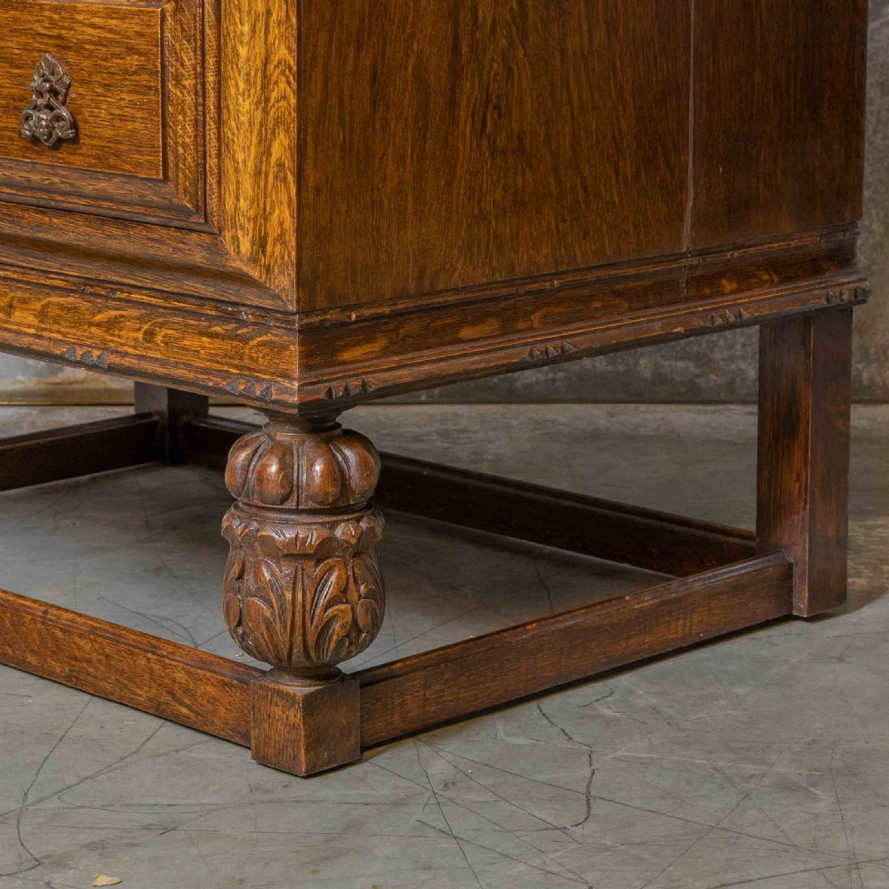 An early 20th-century dark oak writing bureau with a carved oval floral motif on the sloped flap above two drawers. View VII