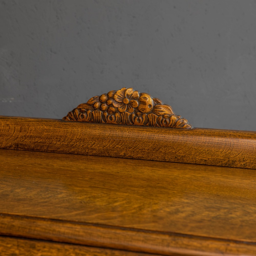 An early 20th-century carved oak display cabinet with a central carved floral panel door flanked by two oval-pattern glazed doors set on turned legs with stretchers. View IX